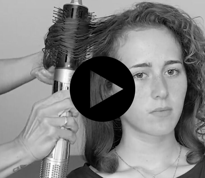 woman with long hair using the style switch round brush to add waves to her hair